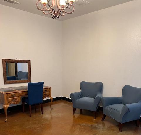 A room with a mirror, table desk, and chairs