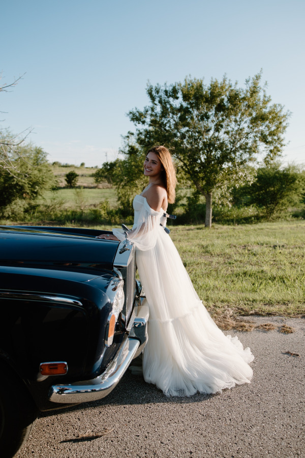 A bride posing outside near a car