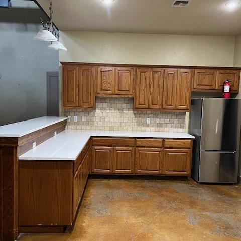 A corner kitchen set-up with cabinets and a fridge