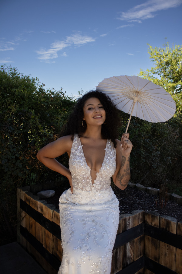 A bride smiles and holds an umbrella