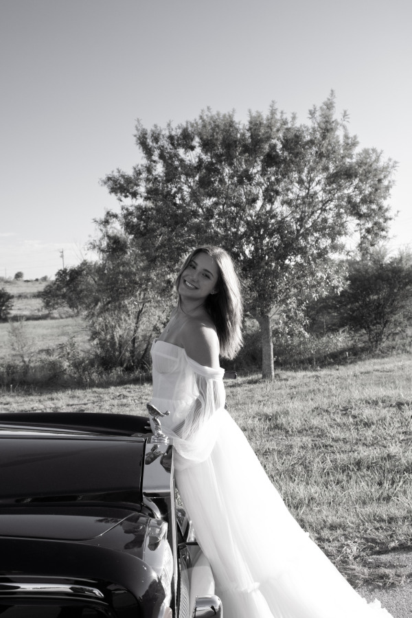 A bride posing with a car
