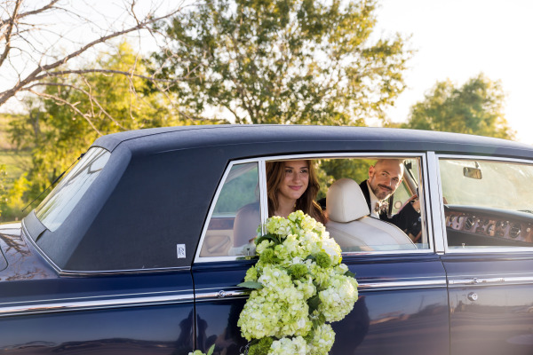 A bride and groom posing in a car