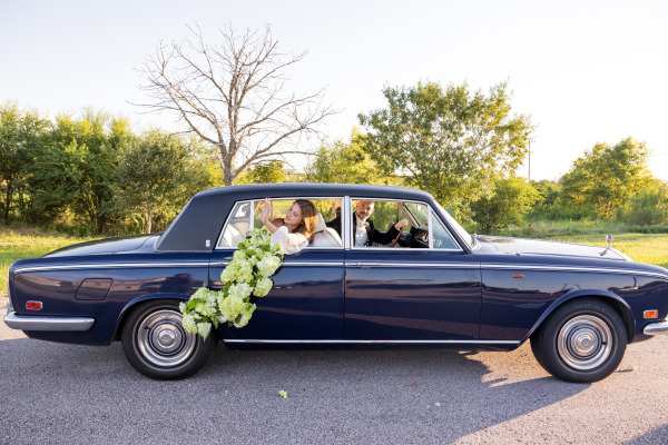 A bride and groom posing in a car