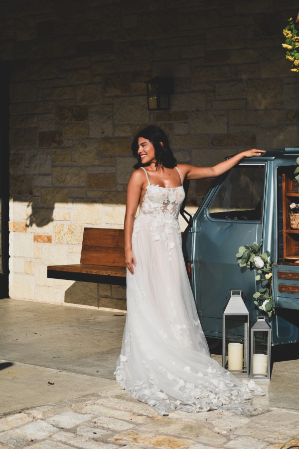A bride posing by a small car