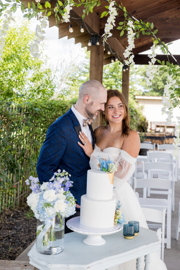 A bride and groom by their wedding cake