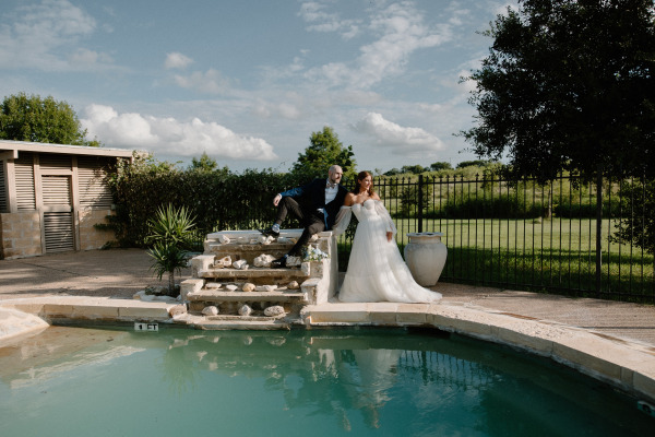 A groom and his bride posing by the poolside