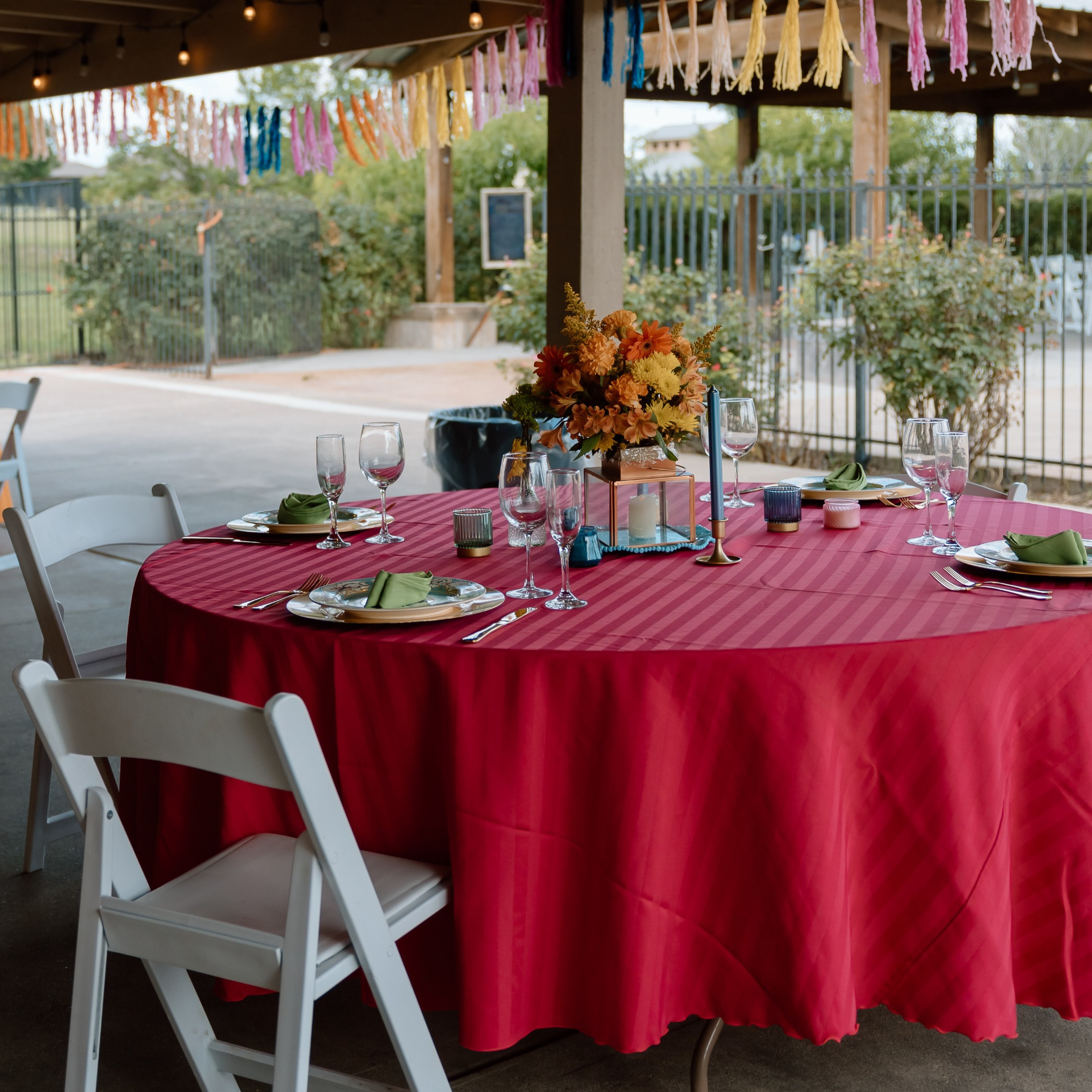 A pink table with a formal table set-up and a white chair on a patio